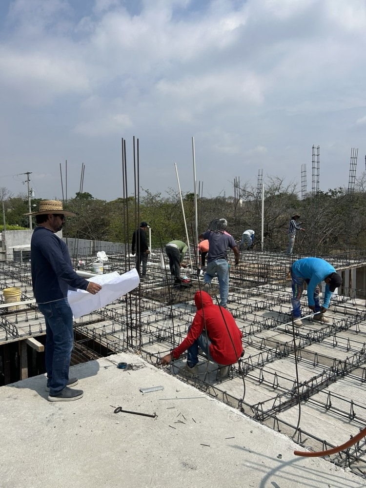 Cuadrilla armando una losa reticular mientras el arquitecto revisa planos